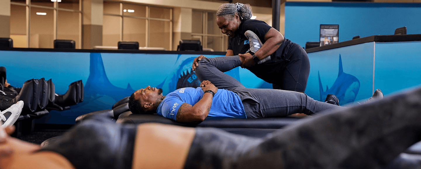 eos staff stretching out the leg and hip of gym member