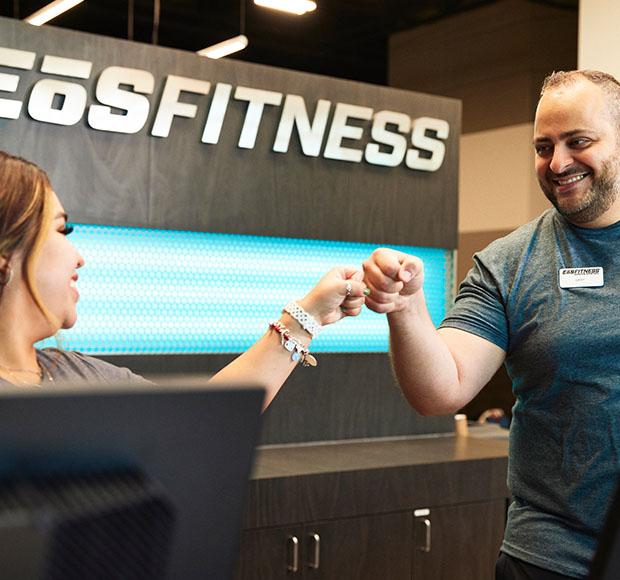 two eos staff at the front desk smiling at each other and fist bumping