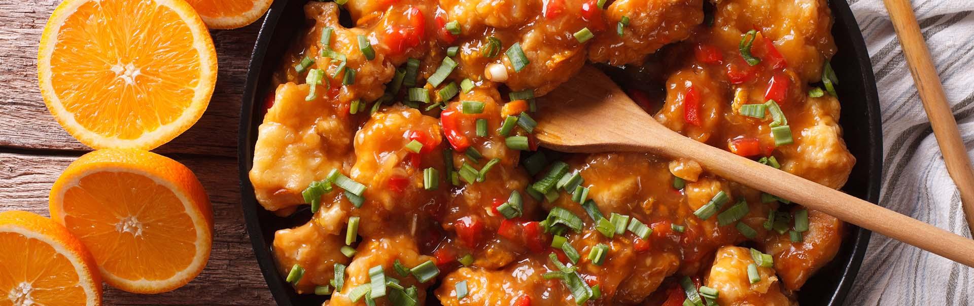 a pot of freshly cooked orange chicken with spikes and herbs